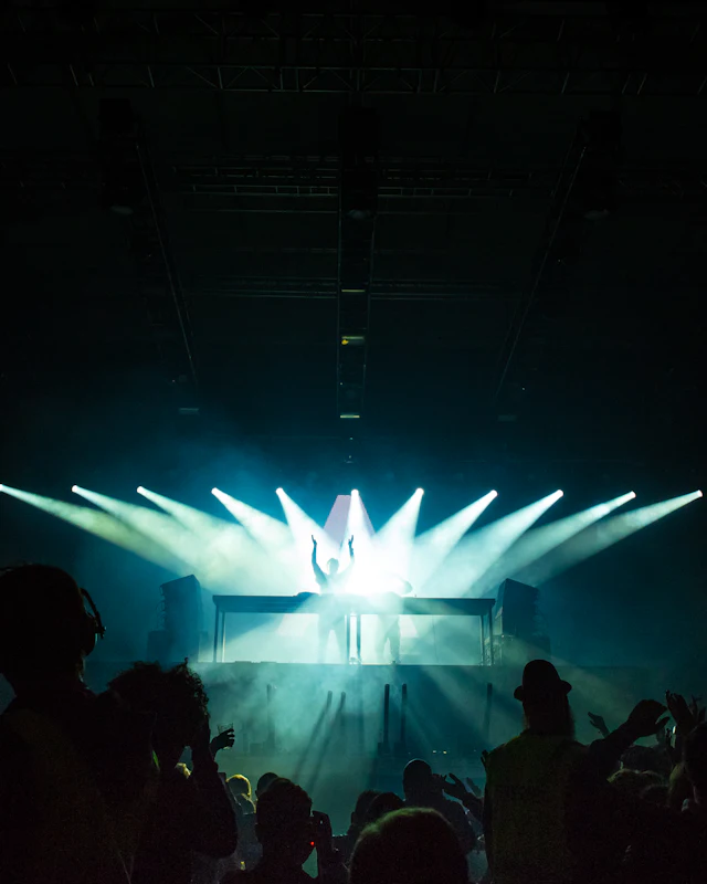 A performer under stage lights facing a cheering crowd